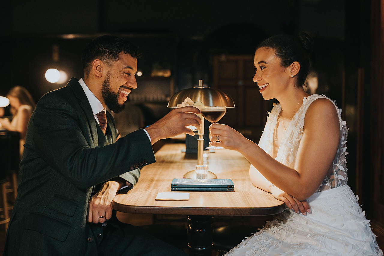 A newly wed couple sitting at a table toasting their special day and looking lovingly at each other