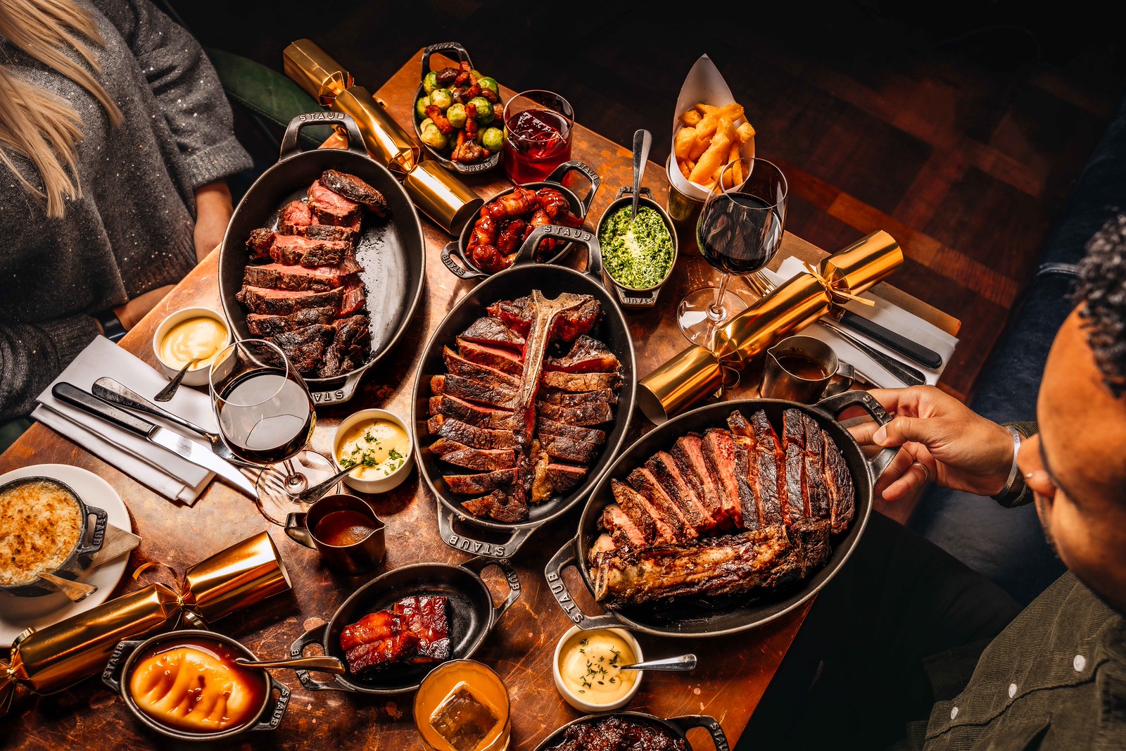 An overhed shot of a generously laden table with sharing steaks and sides